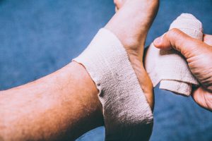 Sport injury shot. Sprained ankle. A leg tensor bandage being applied outdoors. Close up Shot. Retro filter applied